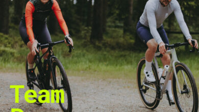 A cyclist woman and man riding mountain bikes together on a forest trail, demonstrating team spirit in triathlon training and outdoor cycling.