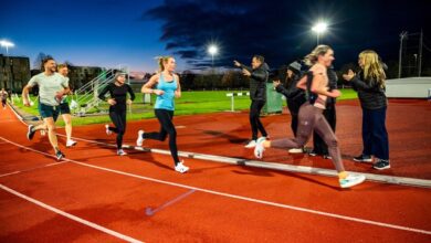 Running group training session at outdoor track during dusk for triathlon athletes.