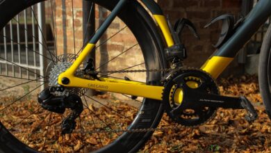High-performance yellow and black road bike frame with Shimano gear system on fallen autumn leaves outdoors.