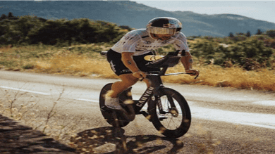 Fastest triathlon cyclist riding mountain bike on open road in natural landscape, high-performance racing bike for multisport endurance events, sunny day outdoor training, competitive triathlon gear focus.