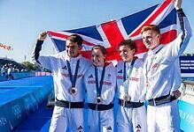British triathlon athletes celebrating with a Union Jack flag after winning medals at the Paris 2024 Olympics.