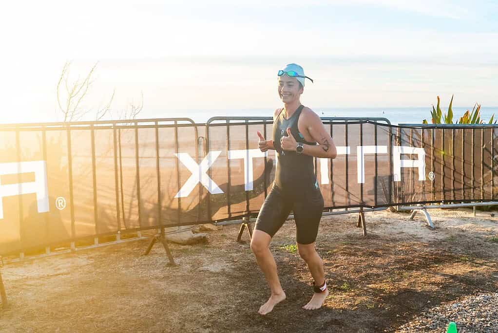 Optimised triathlon athlete running at sunrise on beach during competition, showcasing endurance, training, and personal achievement for triathlon insight SEO.
