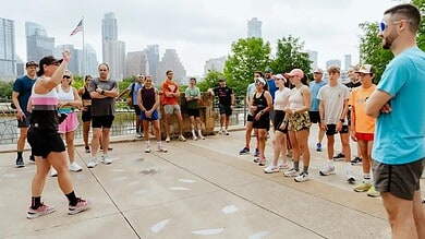 Active triathlon training session outdoors with a coach instructing diverse group of athletes, city skyline in background, focusing on triathlon preparation and fitness motivation.