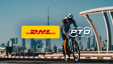 Professional triathlete riding a bike in Dubai with DHL and PTO logos, city skyline in background.