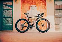 Black and yellow triathlon bike with aerodynamic design leaning against a wall.
