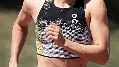 Female triathlete in athletic gear running outdoors during a triathlon event, showcasing endurance and fitness.
