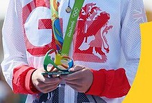 Jonny Brownlee smiling with Olympic gold medal around his neck, wearing Team GB sportswear, during the Olympic medal ceremony.