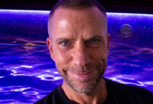 Close-up of a smiling male triathlete with a vibrant blue background, showcasing determination and fitness for triathlon training.